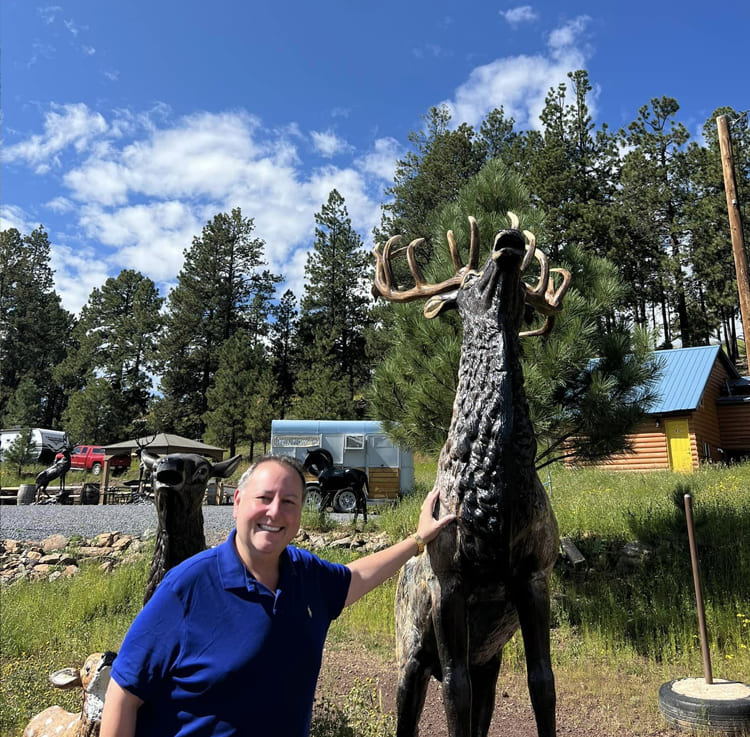 David Toborowsky standing by elk statue, Greer, AZ